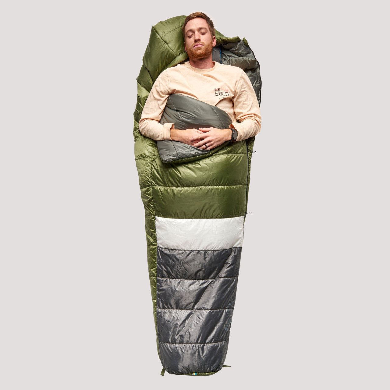 Sierra Designs Shut Eye 20 sleeping bag, green/gray with white stripe, top view, partially opened, with man sleeping on his back